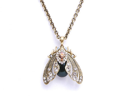 Gold necklace with a pendant featuring a black stone and gemstones on a white background